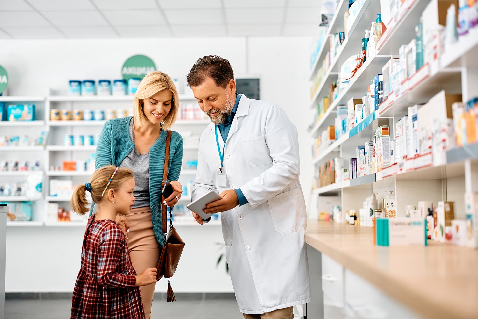 mother and daughter using touchpad with pharmacist