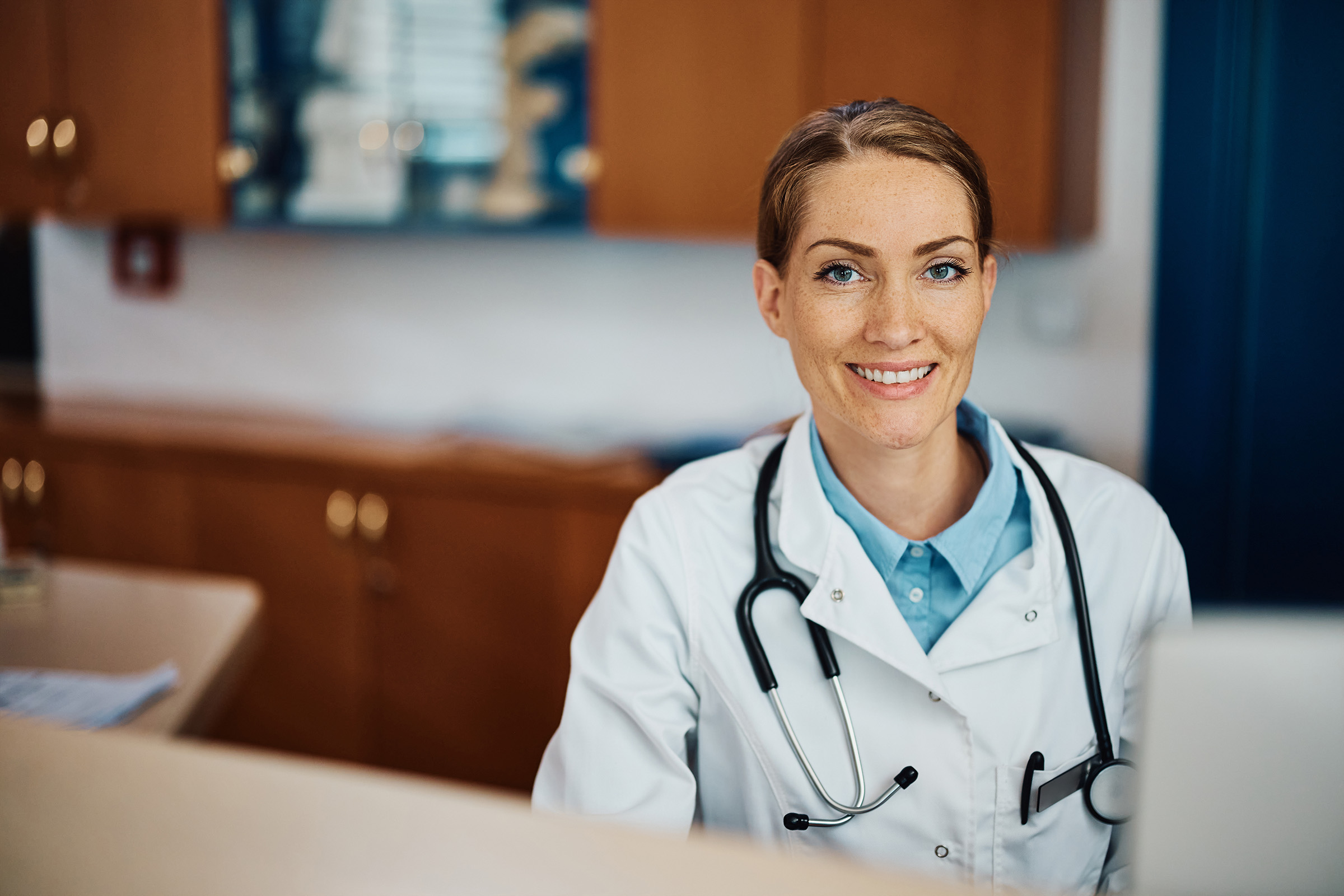 picture of a smiling doctor at her desk in the office